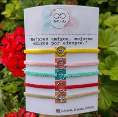 four bracelets with different colored beads and charms on top of each other in front of red flowers