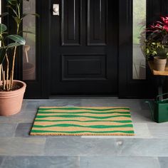 a green and yellow rug sitting on top of a floor next to a black door