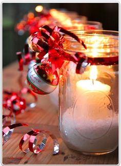 candles are lined up on a table with red ribbon and ornaments around them, along with confetti ornament