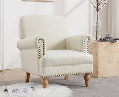 a white chair sitting on top of a rug in a living room next to a vase with flowers