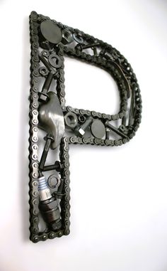 the letter p is made out of chains and other metal parts on a white surface