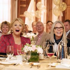 a group of people sitting at a table with wine glasses and plates in front of them