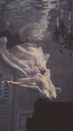 a woman floating in the water next to a chandelier