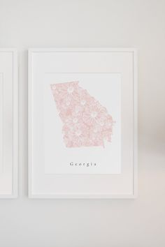 two framed maps are hanging on the wall next to each other, one is pink and white