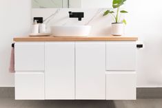 a bathroom with a sink, mirror and potted plant on the counter top in front of it