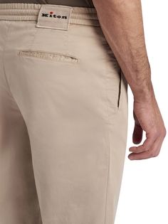 Beige cotton trousers with jogger-style waist. The Kiton trouser, an icon of casual style, is reinterpreted with a relaxed twist thanks to volumes that are roomier at the pelvis, wide on the leg and narrower at the bottom in order to offer an authentic experience of comfort. The drawstring waist with a sporty soul meets darts inspired by the world of tailoring to express the casual and elegant vocation of the garment. The opening of the leg is 18 cm on a base size of 50 (Italian). We recommend hand washing inside-out at 30 C. Dry cleanComposition: 97% Cotton, 3% Elastane, Detail, 100% Cotton Unstructured Cotton Bottoms With Straight Hem, Relaxed Fit Cotton Chinos With Comfort Waistband, Cotton Chinos With Tapered Leg And Belt Loops, Relaxed Fit Chinos With Tapered Leg And Comfort Waistband, Cotton Chinos With Belt Loops And Tapered Leg, Loosely Fitted Cotton Chinos With Tapered Leg, Elevated Casual Tapered Leg Chinos With Elastic Waistband, Elastic Waistband Tapered Leg Chinos For Elevated Casual, Cotton Chinos With Hip Pockets And Tapered Leg