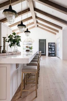 a large kitchen with white cabinets and wooden beams on the ceiling, along with bar stools