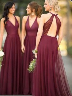 three bridesmaids in maroon dresses standing on the street with their backs to each other