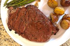 a white plate topped with steak, potatoes and asparagus