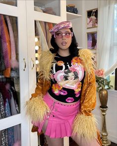 a woman in a pink skirt and jacket standing next to a closet full of clothes