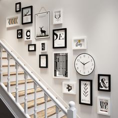 a staircase with many framed pictures on the wall and a clock mounted to the wall