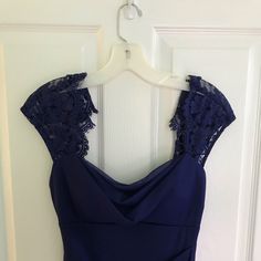 a blue dress hanging on a white door with lace trimmings and an open back