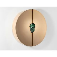 a circular object with a piece of green marble embedded in it's center, on a white wall