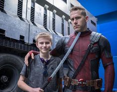 two young men standing next to each other in front of a large truck with ant - man on it