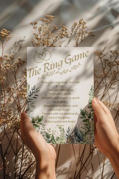 two hands holding up a card that says the ring game with flowers and leaves on it