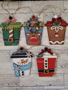 four christmas gift bags hanging on a wooden wall with snowman, reindeer, and santa clause