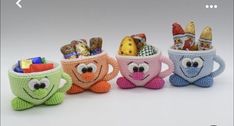 three crocheted mugs filled with candy and candies, each decorated in different colors