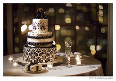 a three tiered cake sitting on top of a table next to wine glasses and candles