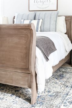 a bed with pillows and blankets on top of it in front of a framed sign