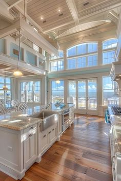 a large kitchen with white cabinets and wood flooring next to an open living room