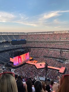 a large stadium filled with lots of people sitting on the bleachers watching a concert