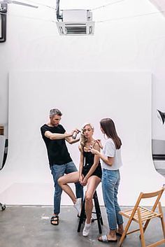 three people standing in front of a white background with an airplane on the wall behind them