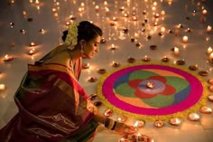 a woman kneeling down in front of a circle of candles