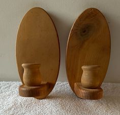 two wooden vases sitting next to each other on a white towel near a wall