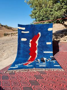 a blue and red blanket sitting on top of a brick floor next to a tree