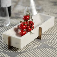 some tomatoes are sitting in a white dish on a table next to a wine glass