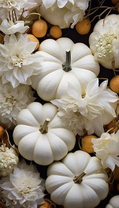 white pumpkins and flowers are arranged on the table