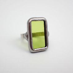 Small, transparent lime green stained glass ring edged in silver. The sterling silver wire band is size 6. This is a one of a kind ring.  Ring Size: US 6 / UK M Center Glass Size: 7/8" x 1/2" Each item by Faerie Glass is 100% uniquely hand-crafted with quality materials that are lead-free. NOTE - All photographs are taken in effort to best represent the actual product. Color of actual jewelry may vary slightly from photographs. Unique Green Rectangular Rings, Green Modernist Ring As A Gift, Modernist Green Ring For Gift, Modernist Green Ring As A Gift, Handmade Green Rectangular Ring, Green Modernist Ring As Gift, Modernist Green Rings For Gift, Modern Green Ring With Rectangular Stone, Modern Green Rectangular Stone Ring