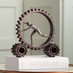 the sculpture is on top of a book and has a man running inside it,