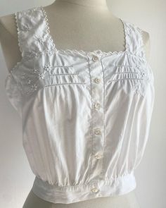 This camisole dates around the 1930s and features floral embroideries around the bust and the straps.  The decorative hems are in half-circle. The monogram OL or OC is embroidered at the left side of the piece. The condition is excellent, there are a few pinholes.  Measurements Bust 36 inches  Waist 26 inches  Length 10 inches  Please message me for further information. Vintage Fitted Tank Top With Spaghetti Straps, Vintage Fitted Spaghetti Strap Tops, Fitted Vintage Tank Top With Spaghetti Straps, Vintage Cotton Top With Square Neck, Cotton Underbust Tops For Summer, Vintage Tops With Lace Trim And Spaghetti Straps, Vintage Lace Trim Top With Spaghetti Straps, Fitted Vintage Camisole, Vintage Cotton Cami Tank Top