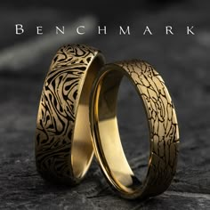 two gold wedding bands with intricate designs on them, one is engraved in the middle