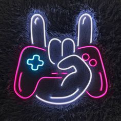 a neon sign with a hand holding a video game controller in the shape of a peace sign