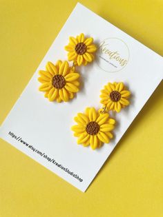 two yellow sunflowers with brown centers are on a card next to a pair of scissors