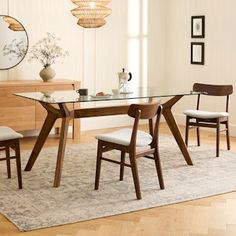 a dining room table with chairs and a rug on the floor in front of it