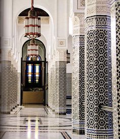 the inside of a building with white and blue tiles on the floor, pillars and windows