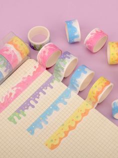 several rolls of washi tape on top of a purple surface next to other items