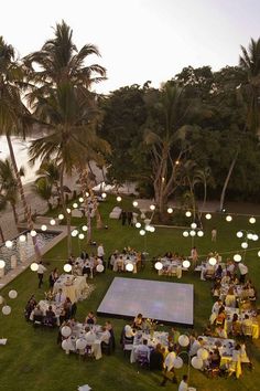 an aerial view of a wedding reception on the lawn by the beach at dusk with palm trees