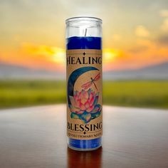 a candle sitting on top of a wooden table next to a field and sky in the background