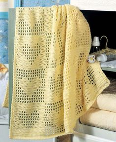 a yellow crocheted blanket sitting on top of a bed