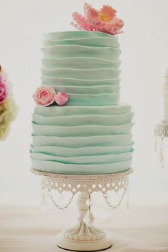 a three tiered cake with pink flowers on top and green icing in the middle