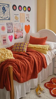 a bed with orange and yellow pillows on top of it next to a white headboard