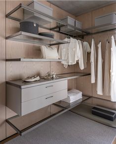 a closet with clothes and shoes hanging on the wall next to shelves filled with shirts