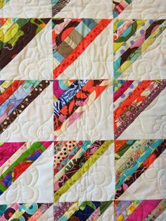 a close up of a quilt on a table topper with many different colored strips