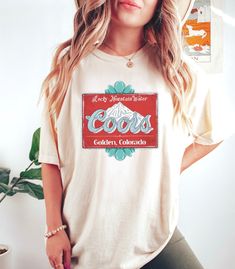 Coors vintage turquoise bead rodeo tshirt! *Thanks for stopping by! Happy Shopping!* This soft-washed, garment-dyed fabric brings extra coziness to your wardrobe while the relaxed fit makes it an excellent daily choice. The double-needle stitching throughout the tee makes it highly durable while the lack of side-seams helps the shirt retain its tubular shape.  .: The Comfort Colors 1717 tee is made with medium fabric consisting of high quality, 100% ring-spun US cotton for long-lasting comfort. .: The relaxed fit keeps the wearer comfy in both casual and semi-formal settings while the crew neckline delivers that classic, neat style which makes it perfect for accessorizing.  .: The pre-shrunk fabric ensures a consistently great fit.  .: All Comfort Colors 1717 shirts feature pre-shrunk cott Vintage Summer T-shirt For Rodeo, Bohemian Graphic Print Rodeo Top, Bohemian Graphic Print Tops For Rodeo, Retro T-shirt For Western-themed Summer Events, Retro Summer T-shirt For Western-themed Events, Vintage Letter Print Tops For Rodeo, Vintage Letter Print Tops For Western-themed Events, Retro Summer Tops For Western-themed Events, Retro Tops For Western-themed Summer Events