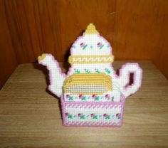 a cross stitch teapot on a wooden table