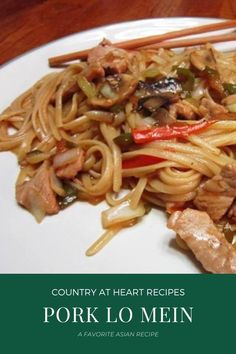 a white plate topped with meat and noodles next to chopsticks on top of a wooden table